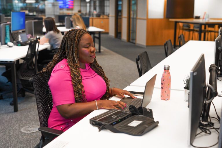 Blind person uses a laptop and braille note to work at a desk