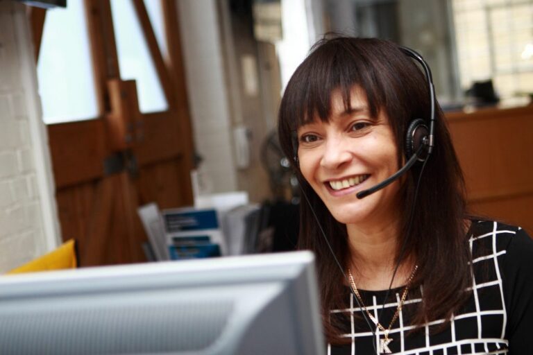 Katherine Beavis with a headset on looking at a computer