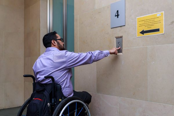 Man in wheelchair calling the elevator