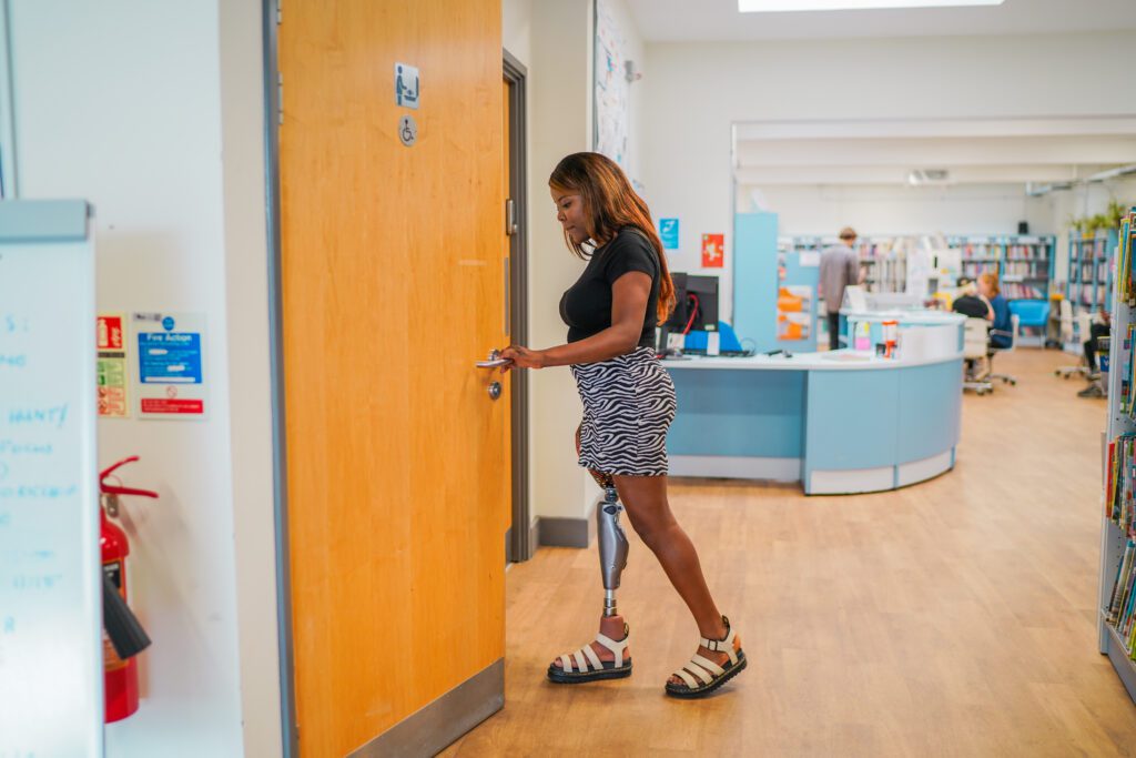 A woman with limb loss / prosthetic leg using accessible toilet in library