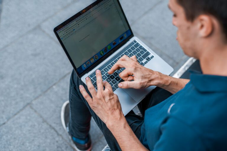 A young man with multiple disabilities uses a laptop outside.