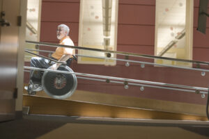 Photo of a man going up a ramp in a wheelchair.