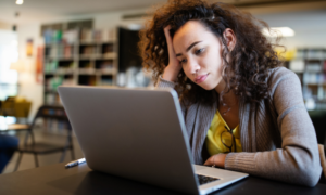 A woman working on a laptop and looking frustrated.