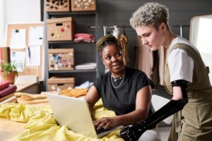 Two people at work discussing what is on a laptop. One person has a prosthetic lower arm.