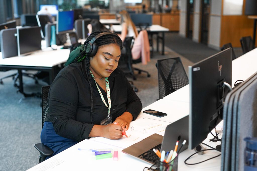 Woman with a less visible disability wears noise cancelling headphones and a sunflower lanyard at work