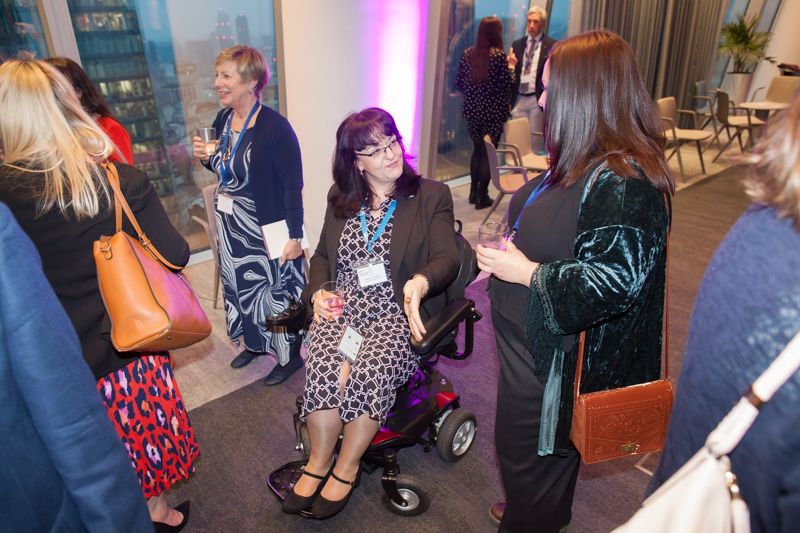 Delegates, including a wheelchair user, networking at an event.