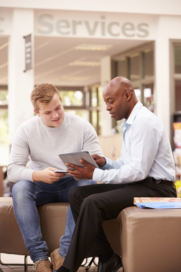 2 people looking at a tablet. Above them is a sign that reads 'Services'.