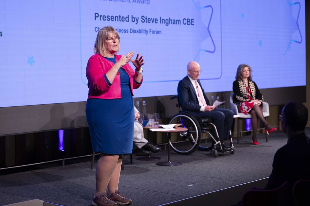 Bsl interpreter signing on stage at the Disability Smart Awards 2024 ceremony.