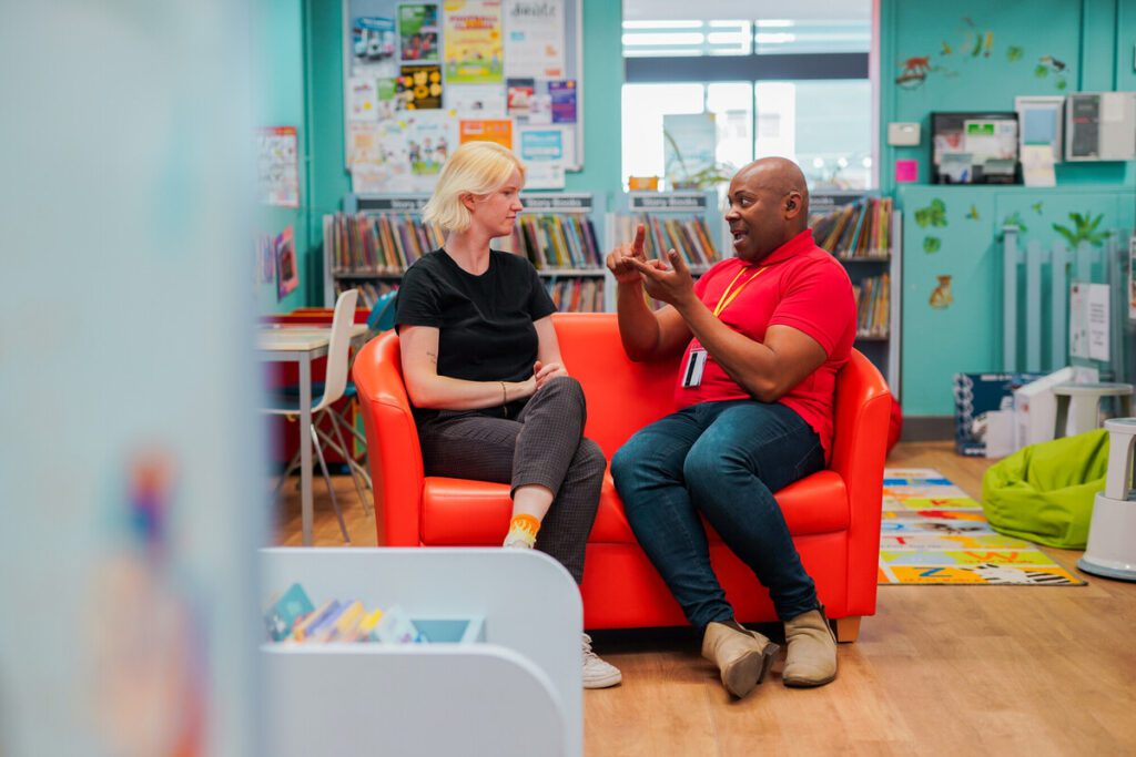 Two people using sign language in a library.