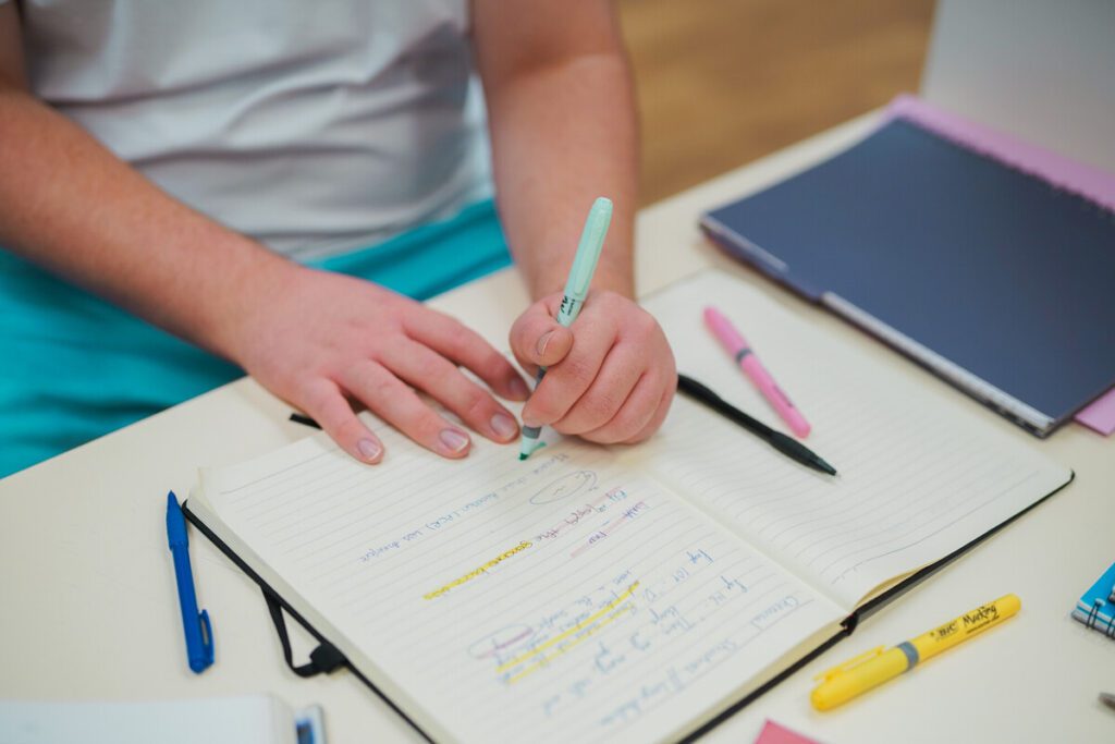 Person using highlighters in a notepad.