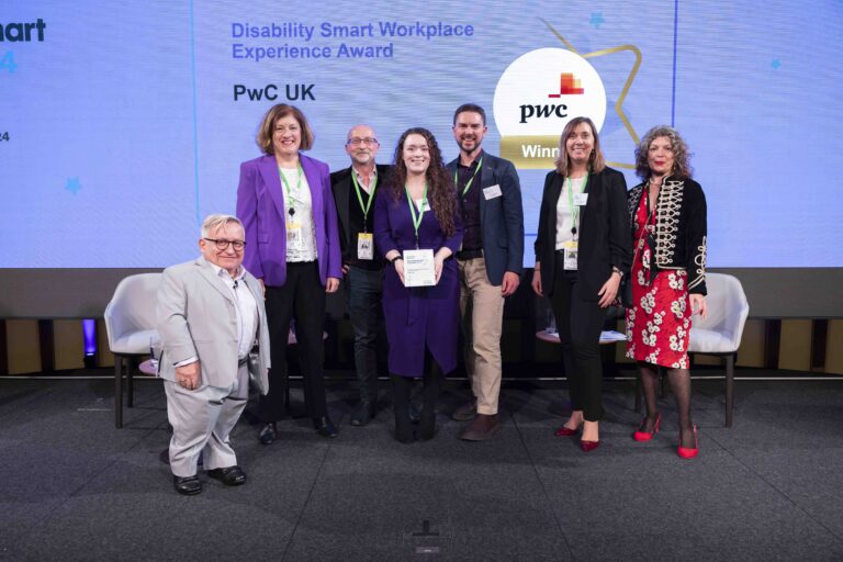 The PwC team posing with their award on stage with co-hosts Diane Lightfoot and Simon Minty at the Disability Smart Awards 2024 ceremony.