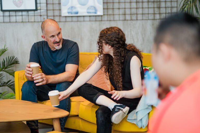 A Deaf person wearing hearing aids has a coffee with family.