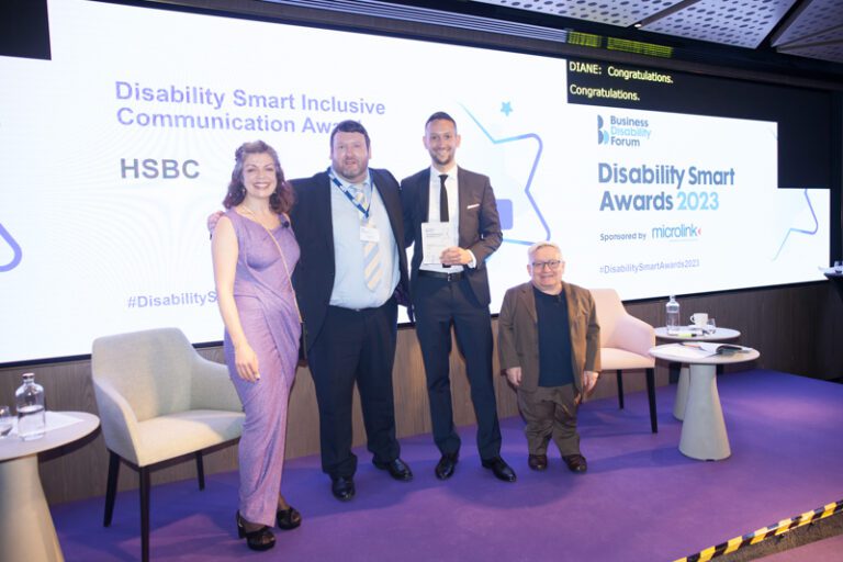 The HSBC team posing with their award on stage with co-hosts Diane Lightfoot and Simon Minty at the Disability Smart Awards 2023 ceremony.