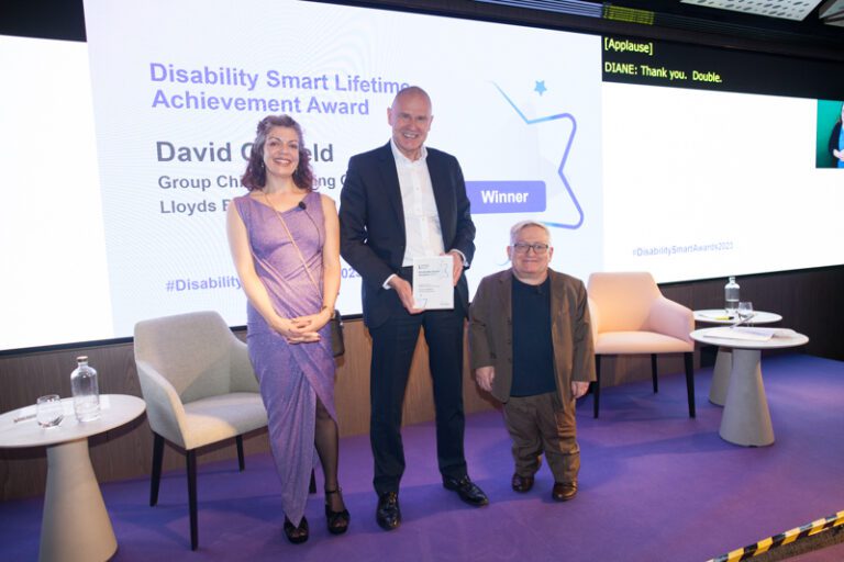 David Oldfied posing with his award on stage at the Disability Smart Awards 2023 ceremony.