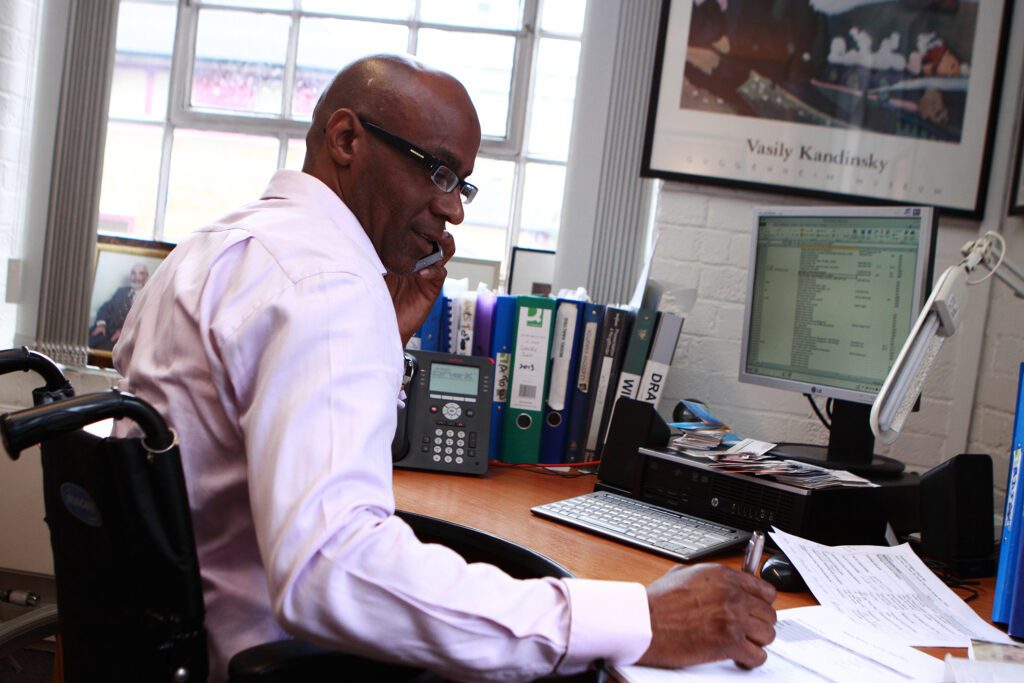 Wheelchair user at his desk on the phone in a office