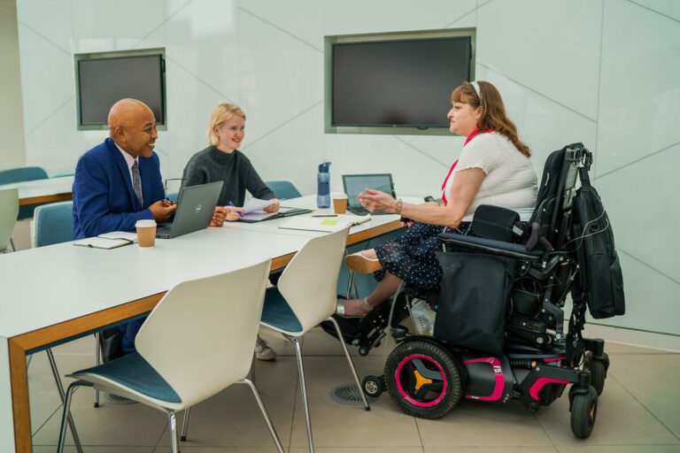 Wheelchair user with Chanarin-Dorfman syndrome meets with two colleagues in an office.