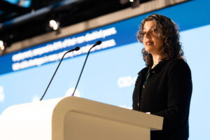 Speaker addressing the audience from behind a lectern onstage at a conference.