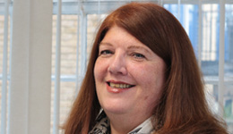 Headshot of Karan Snuggs, a smiling white woman with long ginger hair.