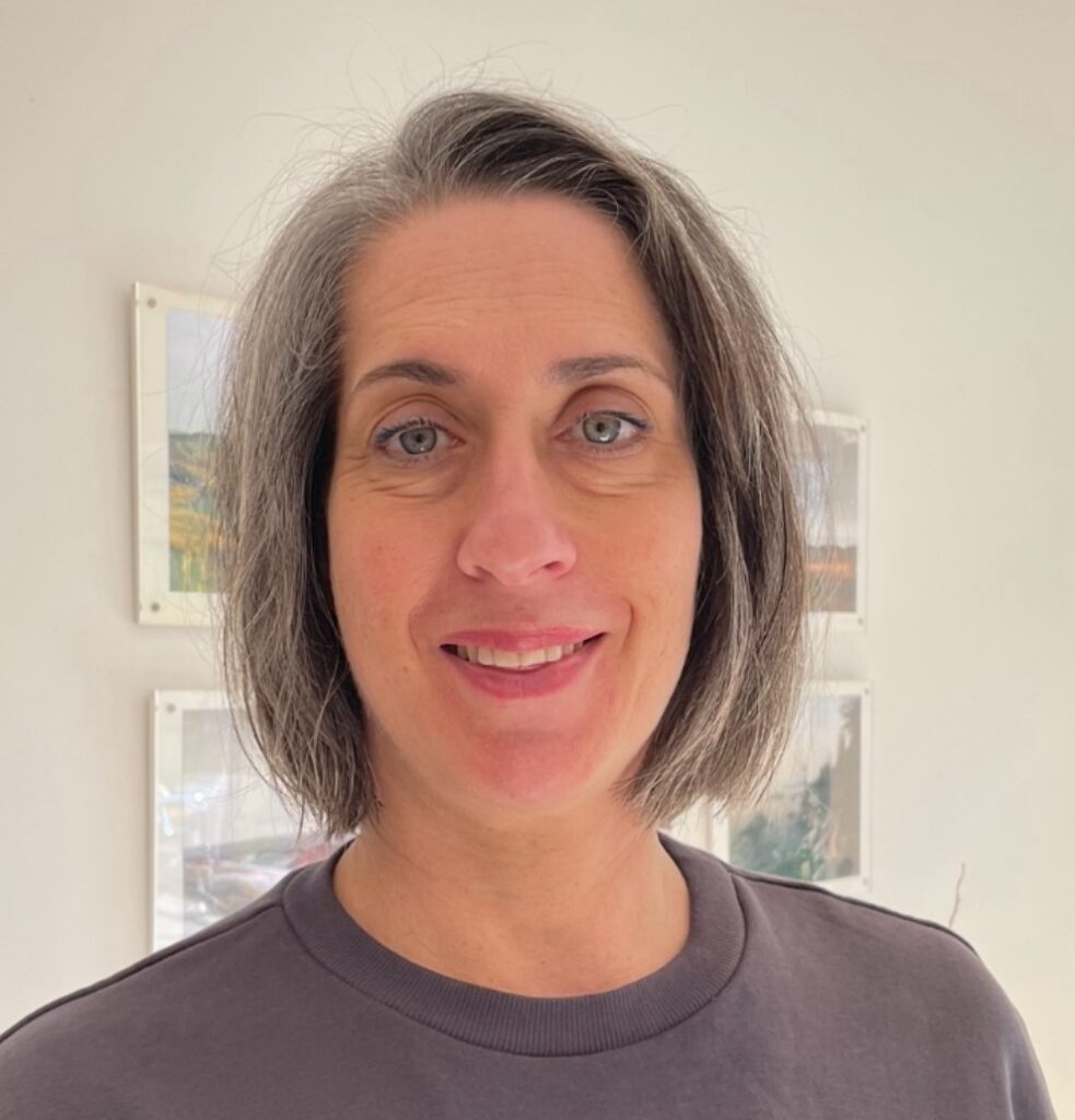 Headshot of Lara Davis, a white woman with short black hair wearing a brown top.