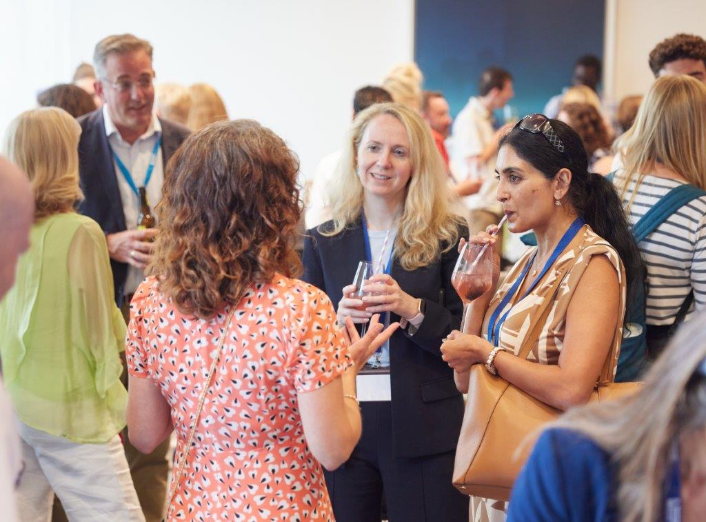 Group of delegates networking at an event. One is sipping a colourful drink through a straw.