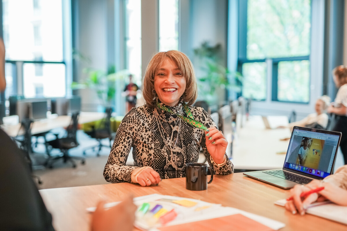 Person with a less-visible disability smiles and holds sunflower lanyard in an office.