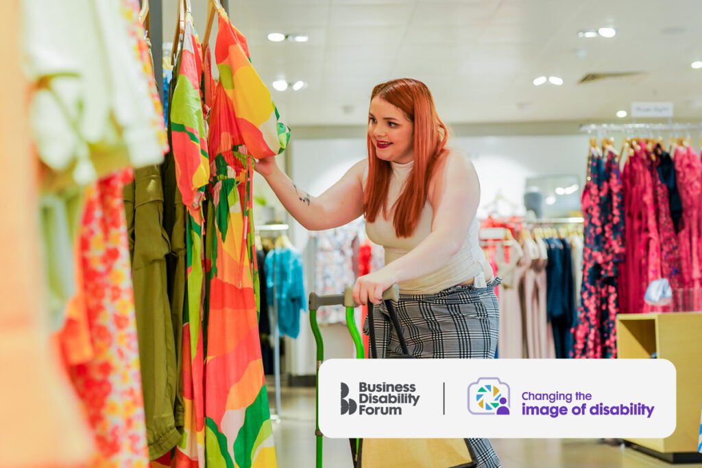 A smiling woman with Cerebral Palsy shops for dresses. She uses two bright green walking sticks.