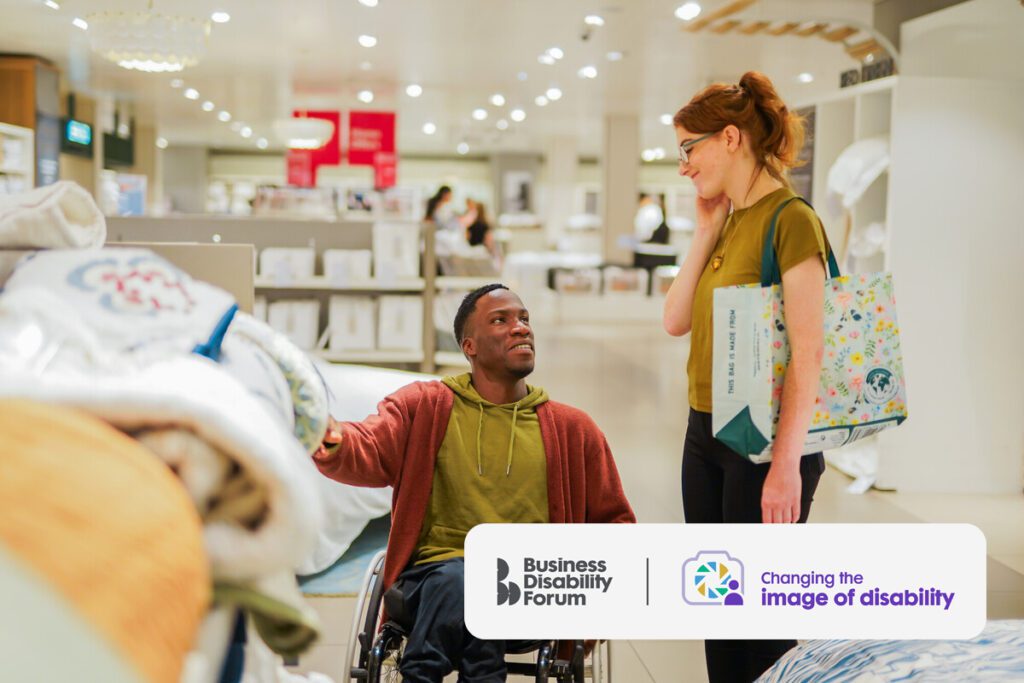 Two friends shop in a home furnishing store. One has a less-visible disability, the other uses a wheelchair.