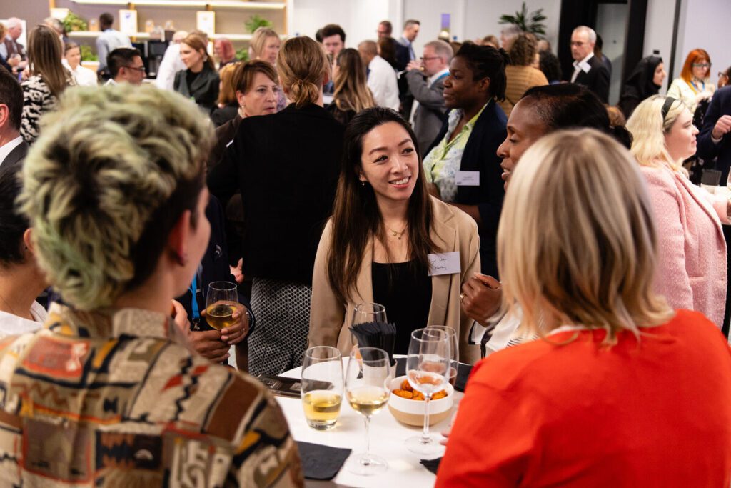 Woman smiling in a crowd of delegates at an event.