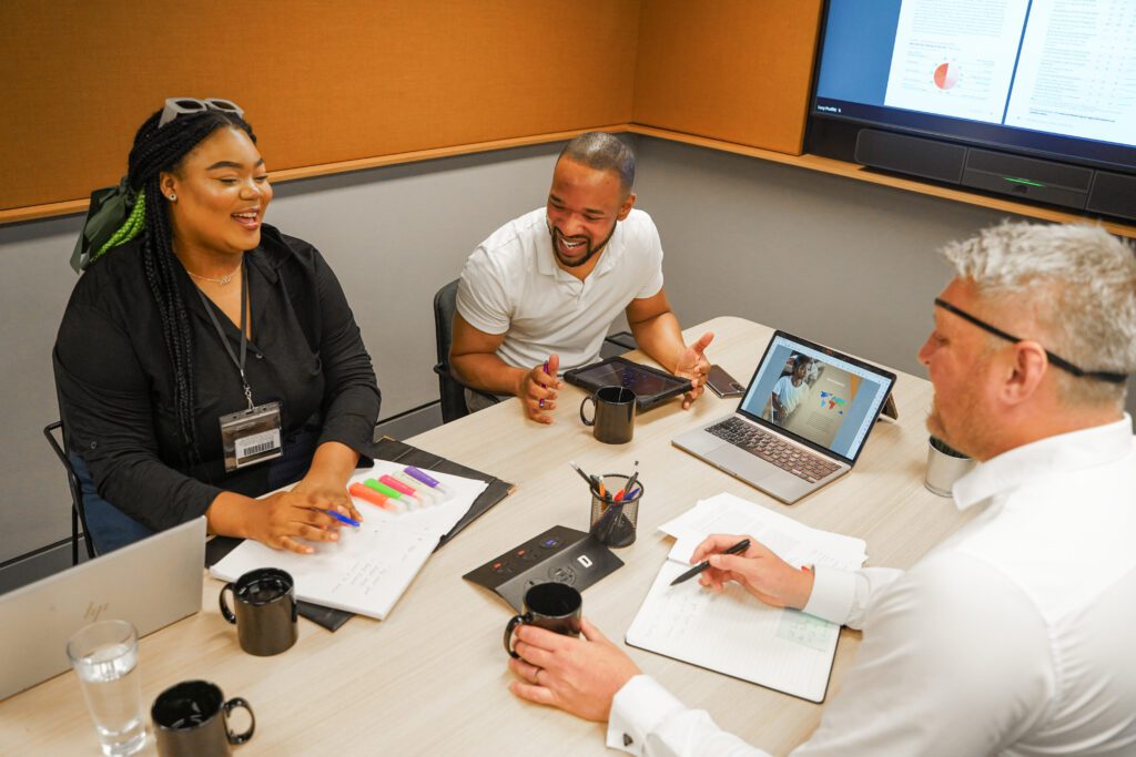 Man with facial difference and sight loss wearing eye patch interacts with colleagues in meeting room