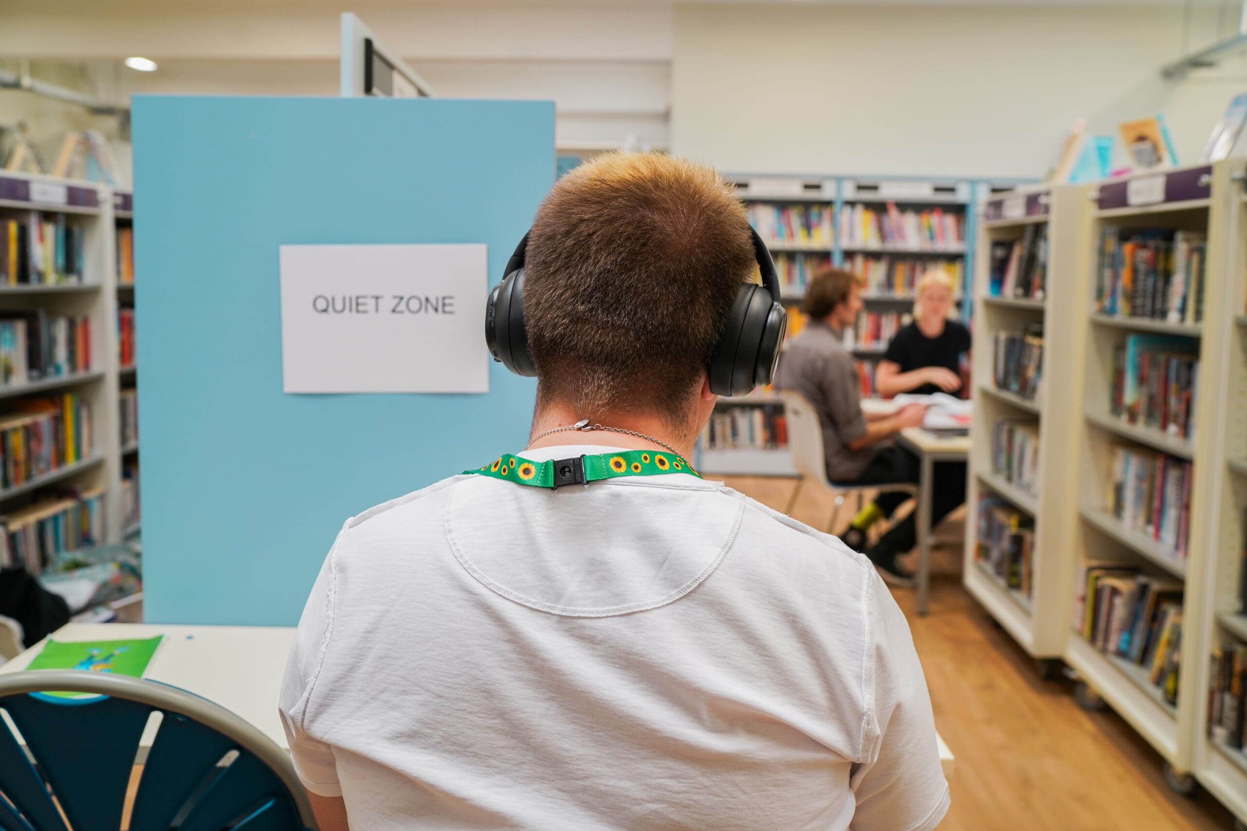 Man with autism studying at a quiet zone in a library wearing noise-cancelling headphones