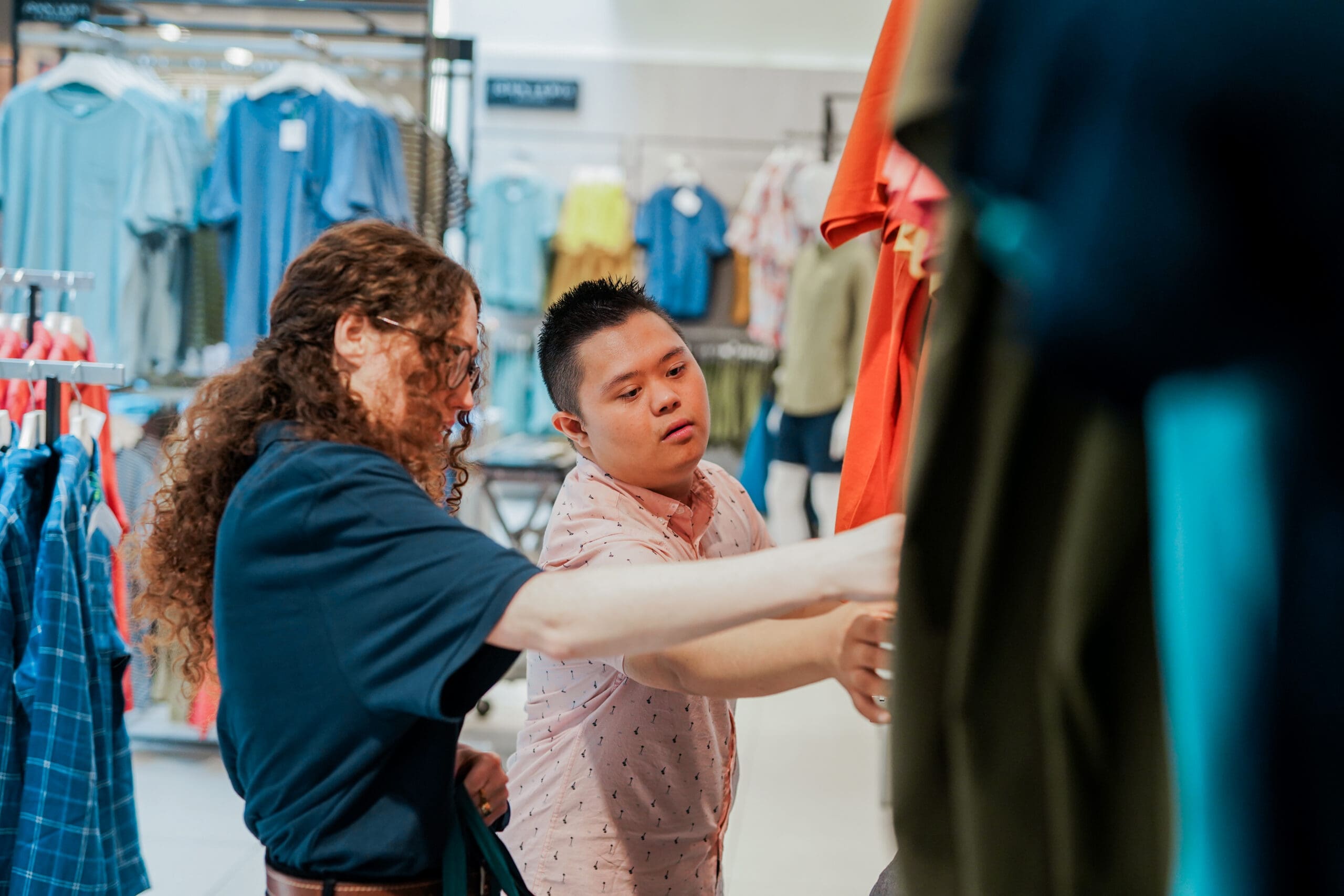 Shop assistant helps a customer with Down’s Syndrome with some clothes in a shop Shop assistant helps a customer with Down's Syndrome with some clothes in a shop.